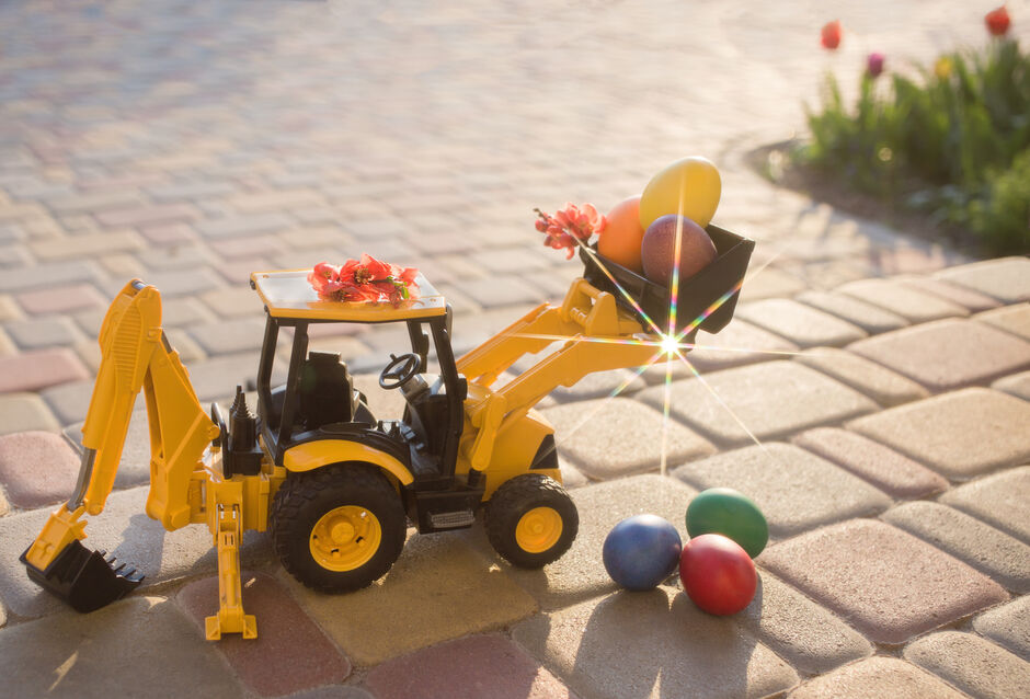 Toy excavator in the sunshine collecting small easter eggs.